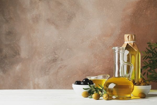 Aceite de oliva - Recipientes con aceite y varias aceitunas de color verde y negras de donde se extrae el líquido