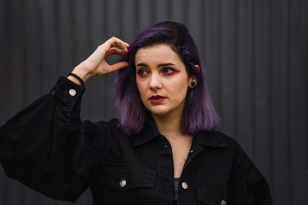 Cortes de pelo para cara redonda - Mujer posando con una mirada distraída con su cabello hasta los hombros, que estilizan su rostro redondo