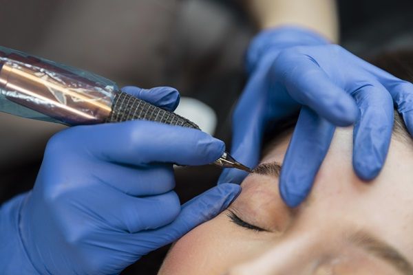 Mujer realizándose el tratamiento de micropigmentación para mejorar la densidad de las cejas y ocultar los espacios de alopecia