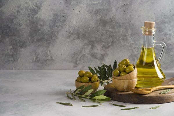 Aceite de oliva - Recipiente con aceite y varias aceitunas verdes para extraer el líquido