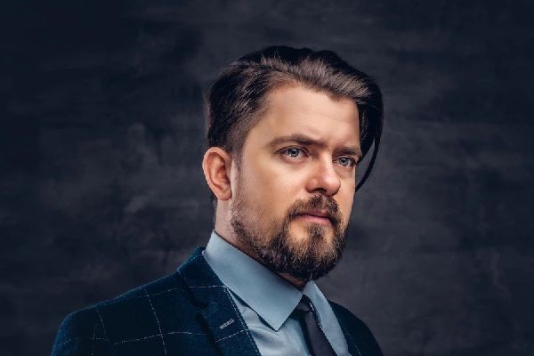 Peinados de hombre para bodas - Hombre con mirada hacia el horizonte, con traje y corte de cabello elegante para el día de su boda
