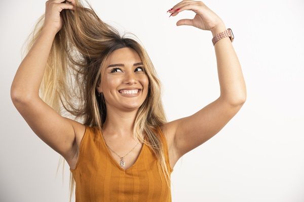 Crecer el pelo - Mujer feliz sosteniendo su cabello largo y sedoso