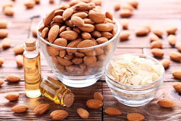 Protector solar - Un tazón de almendras enteros junto a un pequeño frasco de almendras fileteadas para preparar un efectivo aceite hidratante