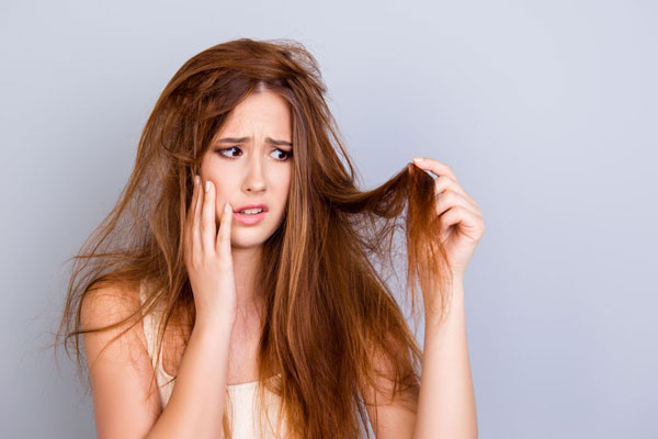 Protector solar - Joven se muestra visiblemente preocupada por el encrespamiento y la resequedad de su cabello 