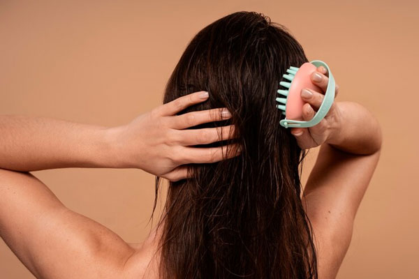 Exfoliantes capilares - Chica de espalda masajea pacientemente su cuero cabelludo de forma manual