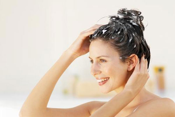 Exfoliantes capilares - Joven visiblemente feliz aplica masajes sobre el cuero cabelludo mientras lava su cabello