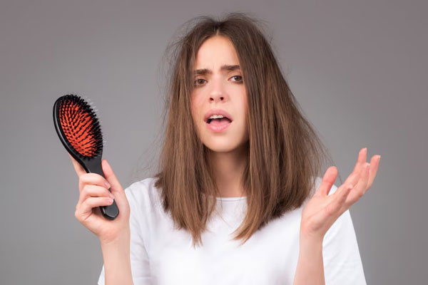 Aceite de ricino para el pelo - Joven se muestra visiblemente preocupada por la pérdida de cabello