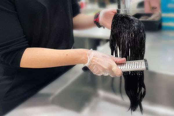 Mujer lava y cepilla con delicadeza un fragmento de cabello postizo para prolongar su duración