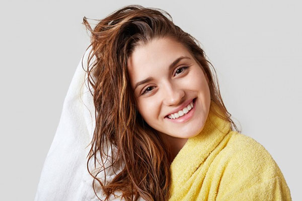 Exfoliantes capilares - Mujer feliz tras darse una ducha e hidratar profundamente su melena
