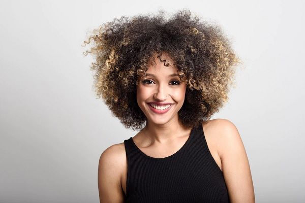 densidad del cabello rizado - mujer con el pelo afro muy sonriente mirando a la cámara