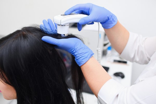 mujer en la consulta de la tricóloga midiendo la densidad de su cabello