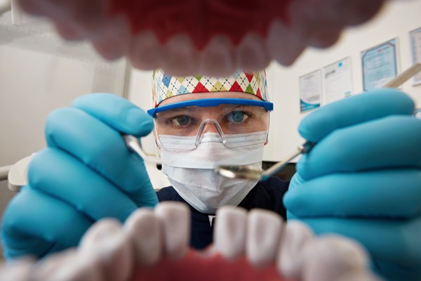 Dentista realizando una limpieza bucal a un paciente, para evitar enfermedades que afecten la salud de sus dientes y cabello