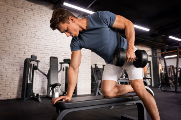 Hombre con abundante cabellera realiza ejercicio para fortalecer sus músculos y brazos en el gimnasio