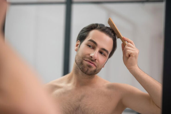 Alopecia en jóvenes - Hombre cepilla su cabellera con peine de madera para evitar el desprendimiento innecesario de las hebras