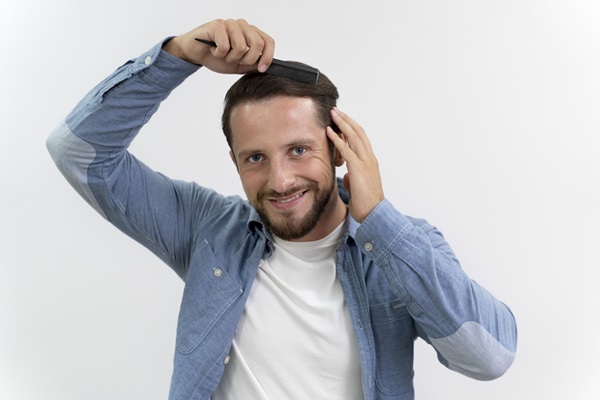 Hombre peinando su cabello con mucha suavidad, para evitar la fricción que pueda dañar los folículos pilosos implantados