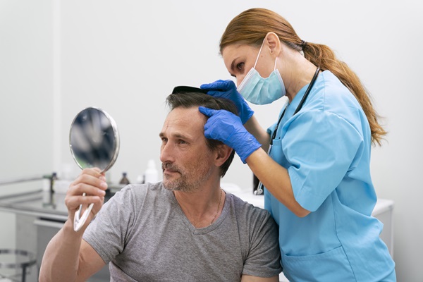 Médico especialista evaluando a un paciente para solucionar los problemas del cuero cabelludo, luego de haberse realizado un injerto de cabello inadecuadamente con un cirujano inexperto