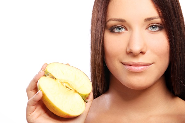 Vinagre de manzana - Mujer sosteniendo una manzana, ya que su líquido ayuda a mantener el tinte del cabello por mayor tiempo