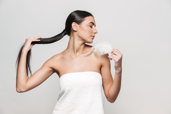 Vinagre de manzana - Mujer tocando su cabello largo y brillante gracias a las propiedades del vinagre de manzana, el cual ayuda a estimular el crecimiento capilar