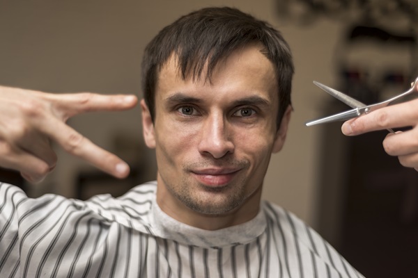 Pelo tras injerto capilar - Estilista cortando el cabello de un hombre con una tijera, para cuidar los folículos pilosos recién implantados