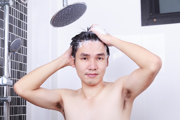 Alopecia juvenil - Hombre joven lavando su cabello con un champú suave y sin químicos, para prevenir la alopecia juvenil