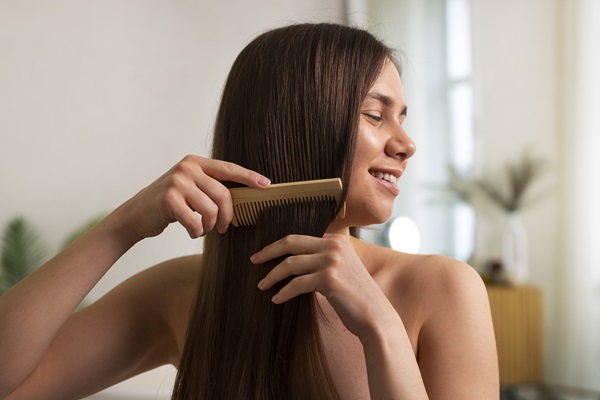 Mujer peinando su cabello liso y brillante, luego de haber aplicado la mascarilla capilar que reduce la grasa del cuero cabelludo
