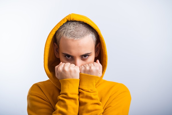 Alopecia juvenil - Hombre joven intentando cubrir su cabello con un suéter, debido a las entradas que están comenzando a aparecer por la alopecia juvenil