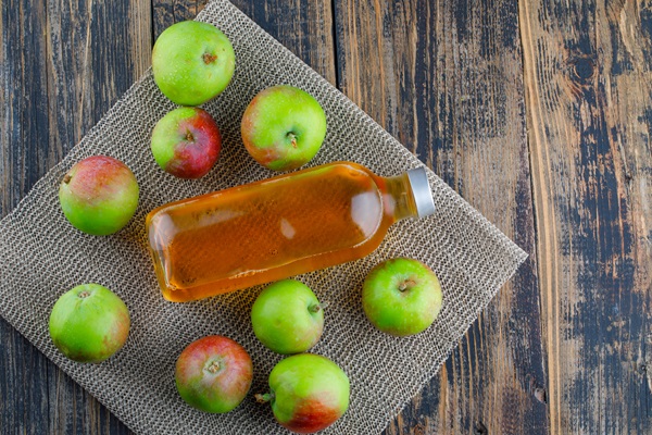 Vinagre de manzana - Imagen de varias manzanas junto a un recipiente que contiene el vinagre de las mismas