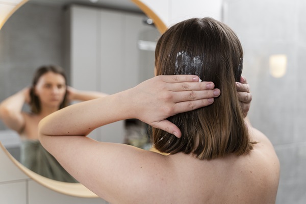 Mujer aplicando una mascarilla con ácido acético en el pelo para combatir la caspa, ya que evita la proliferación del hongo en el cuero cabelludo