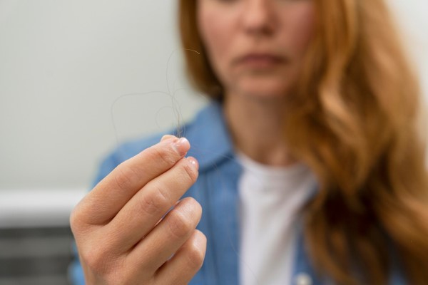 mujer mirando preocupada un mechón de pelo en su mano