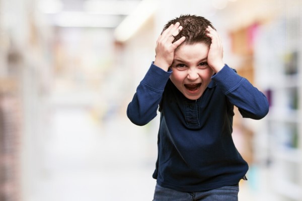  niño llevándose las manos a la cabeza mientras grita