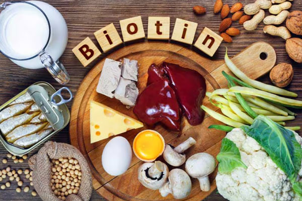 Hígado, huevo, queso, sardinas enlatadas y otros alimentos ricos en biotina servidos sobre una mesa y tabla de madera 