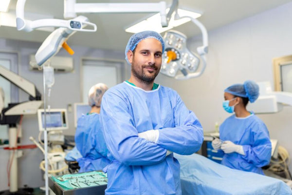 Cirujano de renombre posa frente a la cámara junto su capacitado equipo médico de fondo en el quirófano
