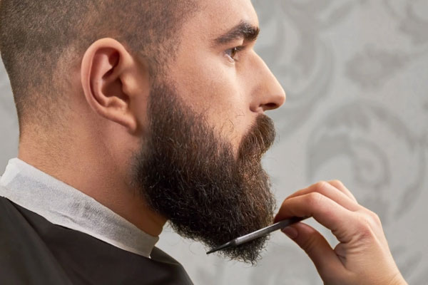 Cuidar la barba - Barbero actualiza el estilo de un cliente mediante un sutil corte de puntas 