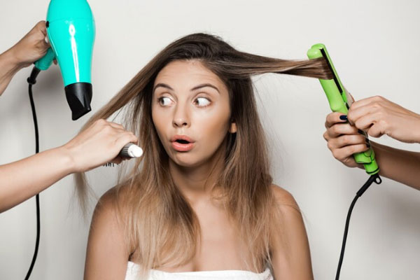 Tips para reparar el cabello dañado - Joven en bata de baño sopesa las consecuencias a largo plazo del uso excesivo de las herramientas de calor
