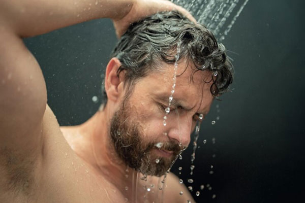 Hombre toma un ducha de agua fría para garantizar la higiene y la salud de su cuero cabelludo