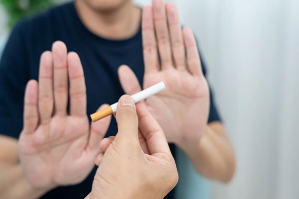 Hombre extiende las manos en señal de rechazo ante el ofrecimiento de un cigarrillo