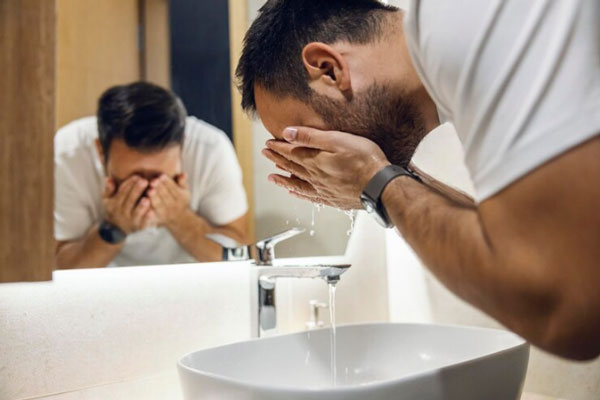 Hombre acude al lavamanos para lavar su cara antes de irse a dormir 