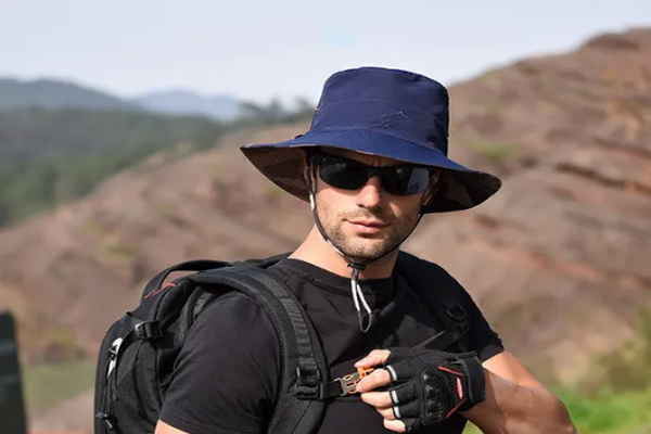 Recomendaciones tras trasplante capilar - Joven deportista usa gorro y gafas para protegerse del sol mientras escala una montaña