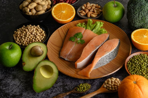 Cabello sano desde adentro - Ruedas de salmón, aguacate, naranja, frutos secos y granos ricos en vitamina A que contribuyen con la preservación de la salud capilar