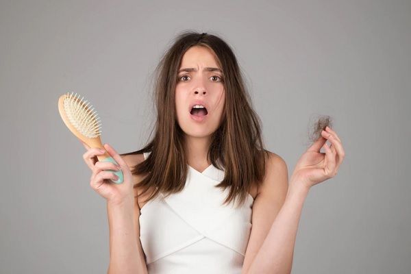 alopecia androgénica en mujeres - mujer joven preocupada con un mecho de pelo en la mano
