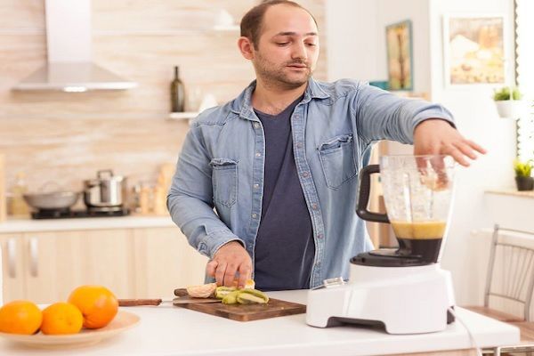caída del cabello por covid - hombre en la cocina preparando un batido de frutas
