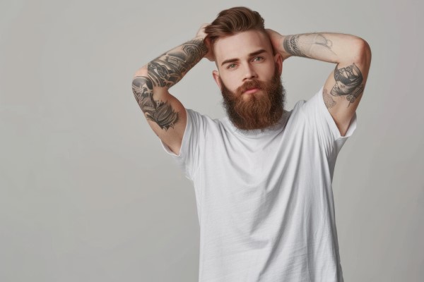 hombre tatuado pasando las manos por su melena