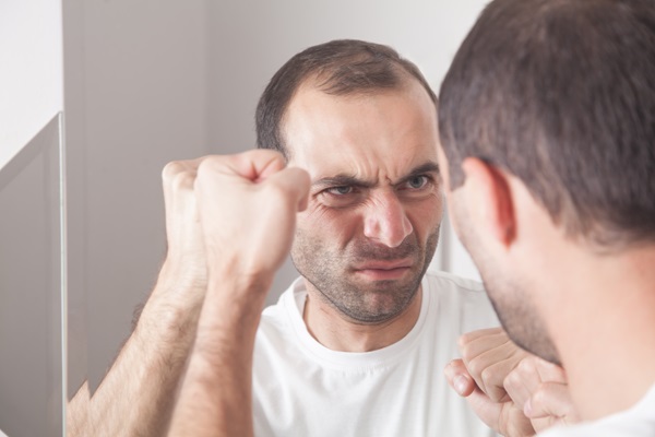 Caspa en los hombres - Hombre coloca los puños en el espejo mientras se observa con cara de enfado