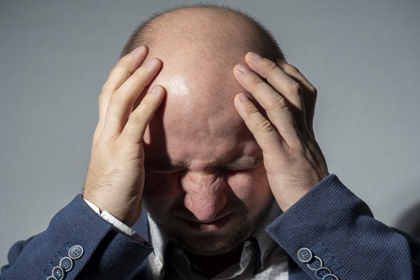 Calvicie afecta a nivel psicológico - Hombre con alopecia estresado coloca sus manos en la cabeza