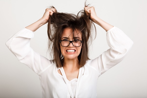 Mujer joven con problemas de estrés jala con fuerza su cabello