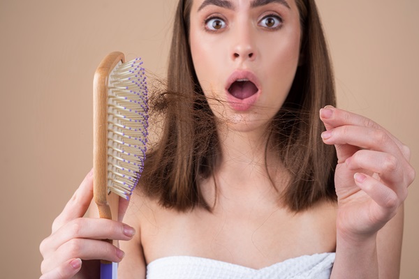 Caída del cabello - Mujer joven con cara de asombro al observar la cantidad de cabello que se cae al cepillarse