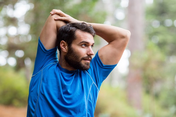 Hombre joven realiza ejercicios de estiramiento al aire libre