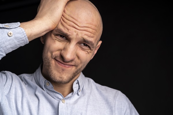 Calvicie afecta a nivel psicológico - Hombre con alopecia tocando su cabeza con cara de preocupación