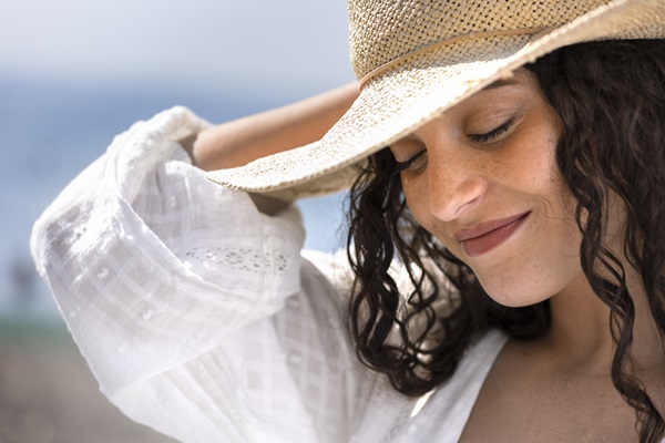 Síndrome de ovario poliquístico - Mujer joven de cabello negro usa un sombrero para protegerse del sol