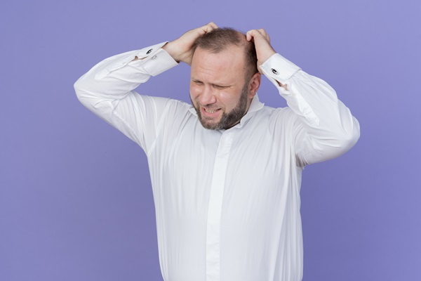 Calvicie afecta a nivel psicológico - Hombre con alopecia en las entradas pone las manos en la cabeza con cara de preocupación